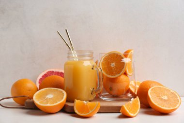 Mason kavanozu dolusu lezzetli meyve suyu ve portakallı beyaz ahşap masa.