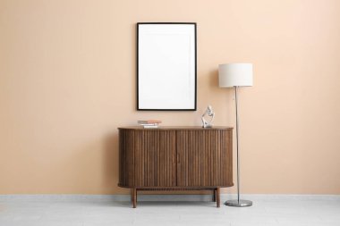 İçinde lamba ve bej duvarda boş poster olan çekmeceler.