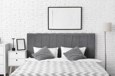 Modern yatak ve beyaz tuğla duvarda boş poster