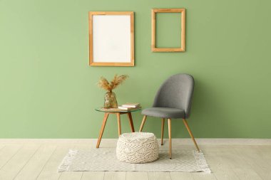 Masalı sandalye, puf ve boş çerçeveler yeşil duvarda