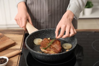 Mutfakta leziz biftek kızartan bir kadın.