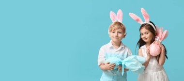 Paskalya hediyeli çocuklar ve açık mavi arka planda tavşan kulaklı çocuklar.