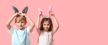 Pembe arka planda paskalya tavşanı kulağı takan şirin çocuklar.