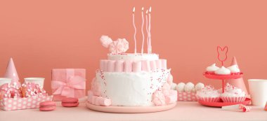 Doğum günü pastası, beyaz masada mumlar ve tatlılar.