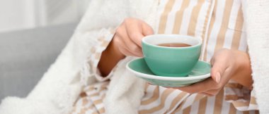 Sabahları bir fincan sıcak çayla genç bir kadın, yakın plan.