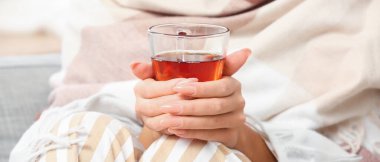 Sabahları bir fincan sıcak çayla genç bir kadın, yakın plan.