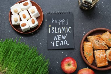 Metni olan bir defter Mutlu İslami Yeni Yıl, koyu arkaplanda tatlılar ve elmalar