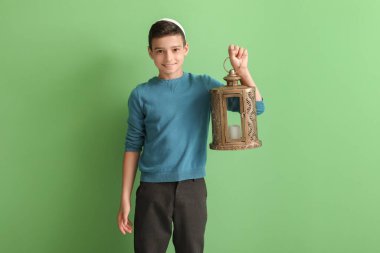 Yeşil arka planda fanatik feneri olan küçük Müslüman çocuk.