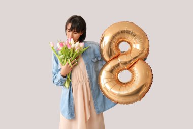 Balon şeklinde 8 figürü ve gri arka planda çiçekleri olan güzel genç bir kadın. Uluslararası Kadınlar Günü