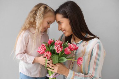 Küçük kız, gri arka planda bir buket güzel çiçekle annesini tebrik ediyor. Anneler Günü kutlaması