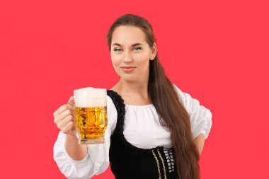 Kırmızı arka planda bir kupa birası olan genç İrlandalı kadın. Aziz Patrick Günü kutlaması