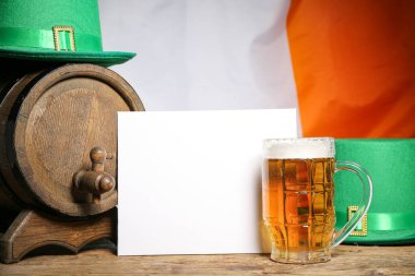 Kupa ve fıçı bira, İrlanda bayrağına karşı masasında leprikon şapkalar olan boş bir kart. Aziz Patrick Günü kutlaması