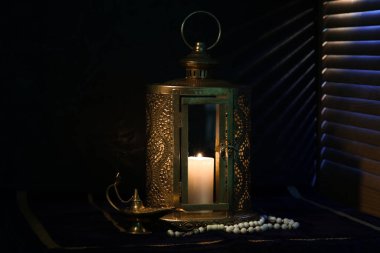 Ramazan ayı için tespih ve Aladdin lambalı Müslüman fener koyu arkaplana karşı masada