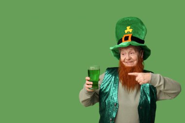Yeşil arka planda kırmızı sakallı cüce şapkalı yaşlı kadın bir bardak birayı işaret ediyor. Aziz Patrick Günü kutlaması