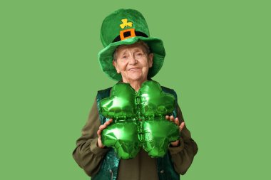 Yeşil arka planda yonca şeklinde hava balonu olan cüce şapkalı yaşlı kadın. Aziz Patrick Günü kutlaması