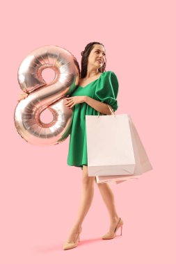 8 numaralı figür şeklinde balonu ve pembe arka planda alışveriş torbaları olan güzel bir kadın. Uluslararası Kadınlar Günü