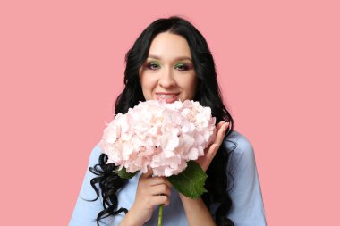 Pembe arka planda ortanca çiçekleri olan güzel genç bir kadın. Uluslararası Kadınlar Günü