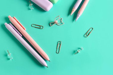 Turkuaz zemin üzerinde ataç olan kalemler