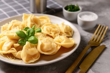 Gri arka planda peynirli ve fesleğenli haşlanmış hamur köftesi tabağı.