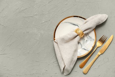 Gri arkaplanda altın çatal bıçak seti olan güzel bir masa.