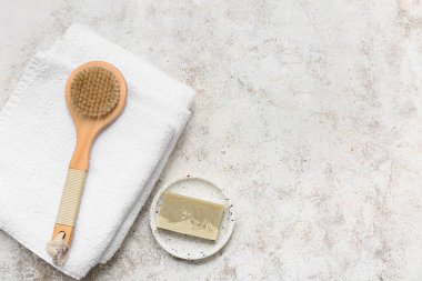 Temiz yumuşak havlular, vücut masajı fırçası ve grunge arka planda sabun çubuğu.