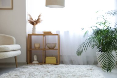 Şık oturma odasının içinde kanepe, raf ünitesi ve ışık perdeleri, bulanık manzara.