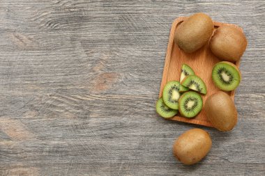 Gri ahşap arka planda taze kivi olan tahta.