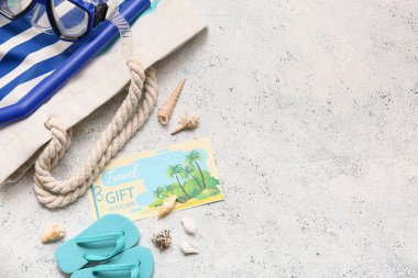 Seyahat hediye çeki, plaj aksesuarları ve hafif arka planda deniz kabukları içeren kompozisyon