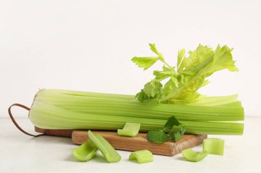 Beyaz zemin üzerinde taze yeşil kereviz demeti ile ahşap tahta tahta