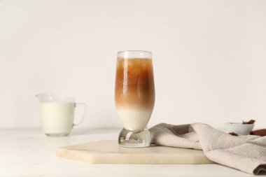 Beyaz arka planda bir bardak buzlu latte ve bir sürahi süt.