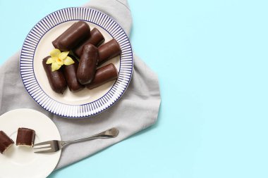 Açık mavi arka planda vanilya aromalı lezzetli çikolatalı kaymak şekerli tabaklar.