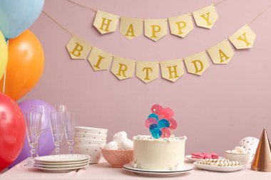 Pasta, şeker ve doğum günü partisi için pembe duvarlı bir masa.