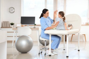 Klinikte küçük bir hastayla çalışan kadın osteopat.