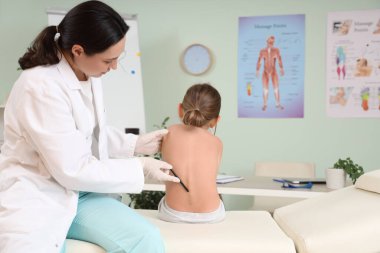 Kadın osteopat klinikteki kanepede küçük bir hastayla çalışıyor.