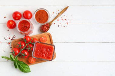 Cam kase ve beyaz ahşap arka planda fesleğenli domates sosu.