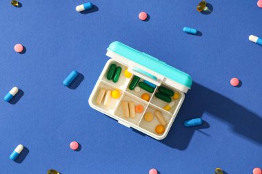Plastik kap ve mavi arka planda haplar. Üst görünüm