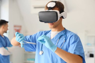 Klinikte VR gözlüğü kullanan makaslı bir erkek doktor.