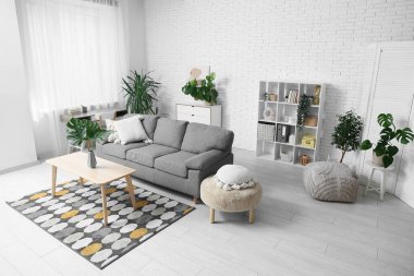 Masada ve şık koltukta tropikal canavar yaprakları olan modern bir oturma odası.