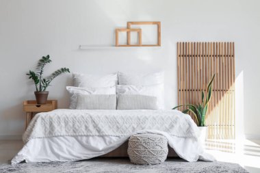 Yatak odasının içinde büyük, rahat bir yatak, puf ve bitkiler var.