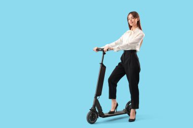 Mavi arka planda modern elektrikli scooterı olan genç ve güzel bir iş kadını.