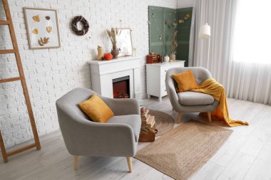 Koltuklar, şömine ve oturma odasının içinde sonbahar ışıkları olan katlanan ekran.