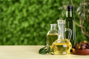 Dekan ve taze zeytinyağı şişeleri dışarıda, ahşap masada.