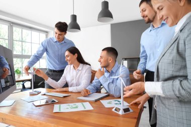 Ofisteki masada rüzgar türbini modelleriyle çalışan bir grup mühendis.