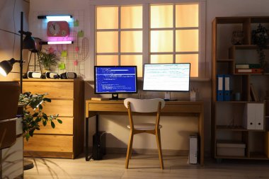 İşyeri, raf ünitesi ve geceleri parlayan lamba olan programcı ofisinin içinde.