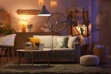 Koyu renk oturma odasının içinde bisiklet, kanepe, sehpa ve parlak lambalar.