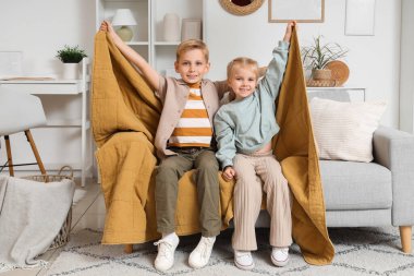 Ekoseli çocuklar evdeki kanepede oturuyor.