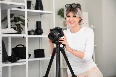 Profesyonel fotoğraf makinesiyle stüdyoda fotoğraf çeken genç ve güzel bir bayan fotoğrafçı.