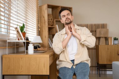 Evdeki masanın yanındaki tiroit bezini inceleyen yakışıklı bir adam.