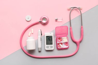 Kalemli modern glukometre, insülin ampulü, steteskop ve renkli arka planda haplar