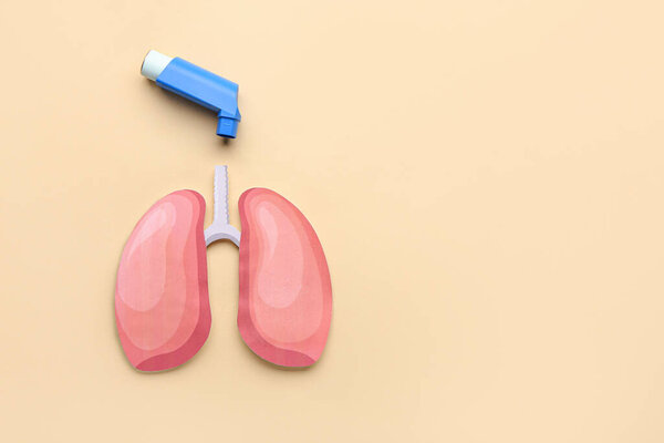Inhaler and paper lungs on beige background